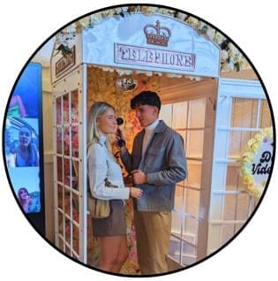 Paar steht lachend in der Videofon-Telefonzelle auf der Hochzeit – emotionale und unterhaltsame Idee für das Videogästebuch