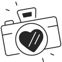 Schwarz-Weiß-Illustration einer Kamera mit einer Herzform in der Mitte des Objektivs und Linien um sie herum, die Bewegung oder Aufregung suggerieren.